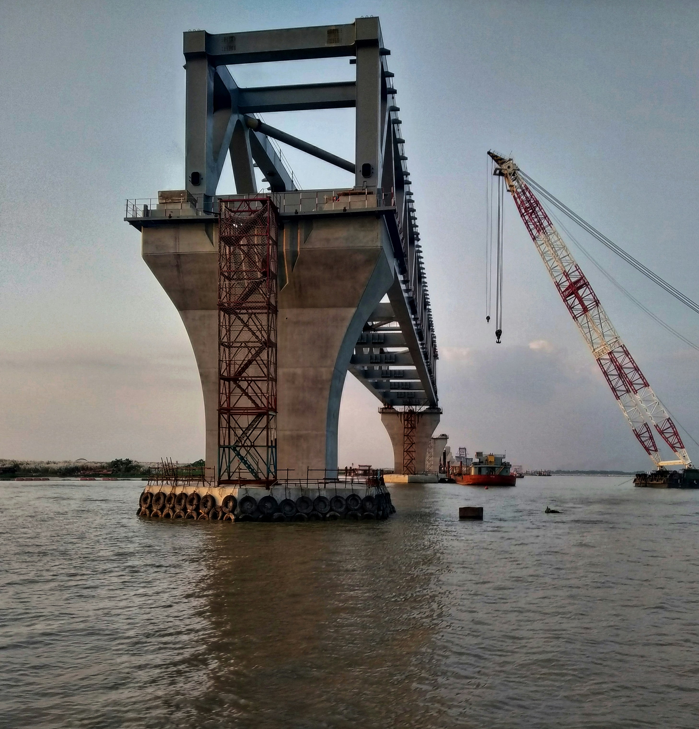 Viaducto de concreto en construcción sobre río con maquinaria pesada