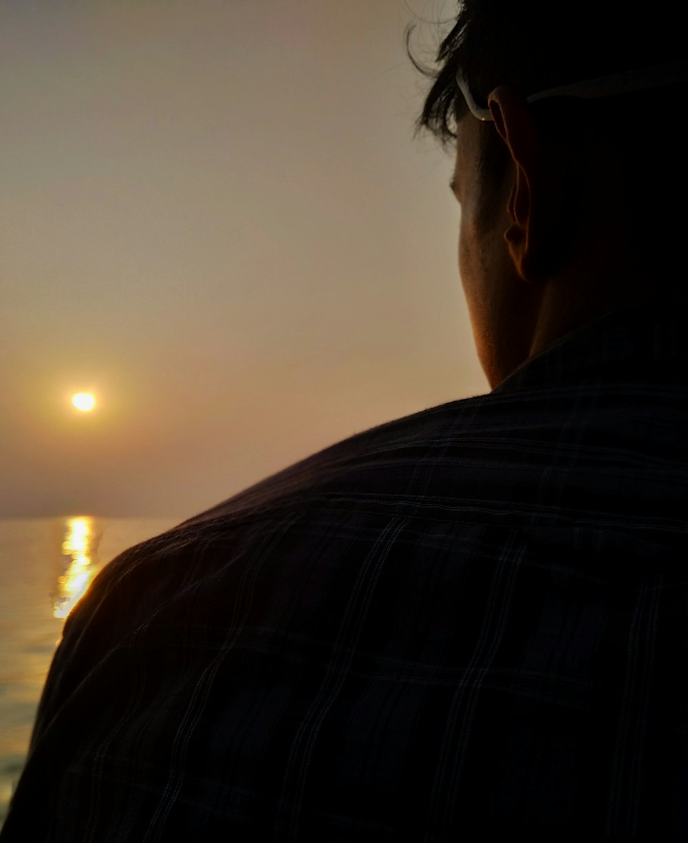 a man looking out at the ocean at sunset