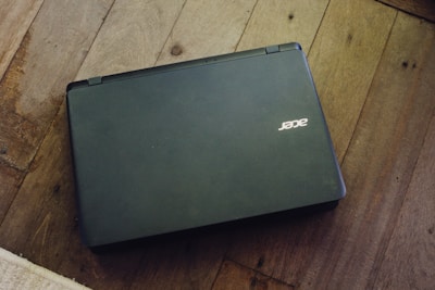 Technician repairing an Acer gaming laptop with green Acer branding visible.