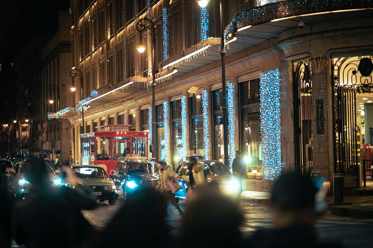 A downtown street at night with buildings wrapped in holiday lights