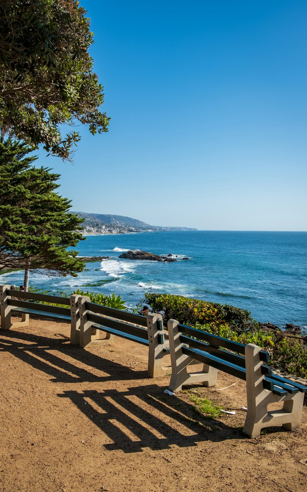 a couple of benches sitting on top of a sandy beach