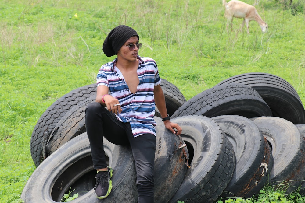 a man sitting on top of a pile of tires