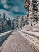 a person riding a snowboard down a snow covered road