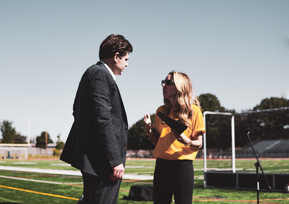 a man in a suit and tie talking to a woman in a yellow shirt