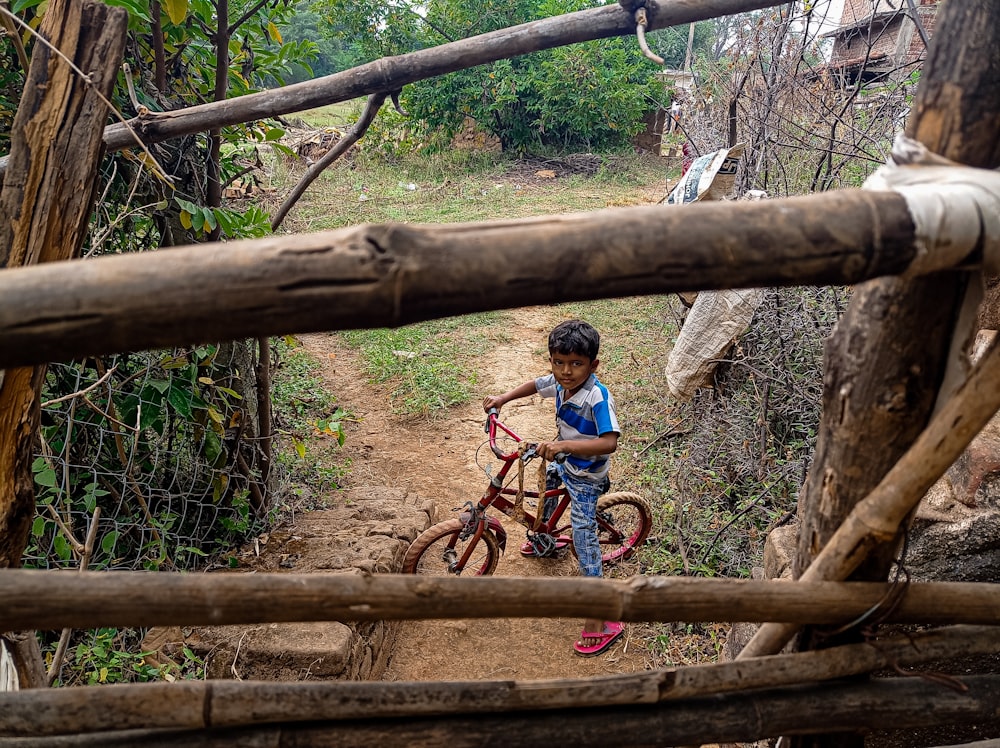 a young boy riding a bike down a dirt path