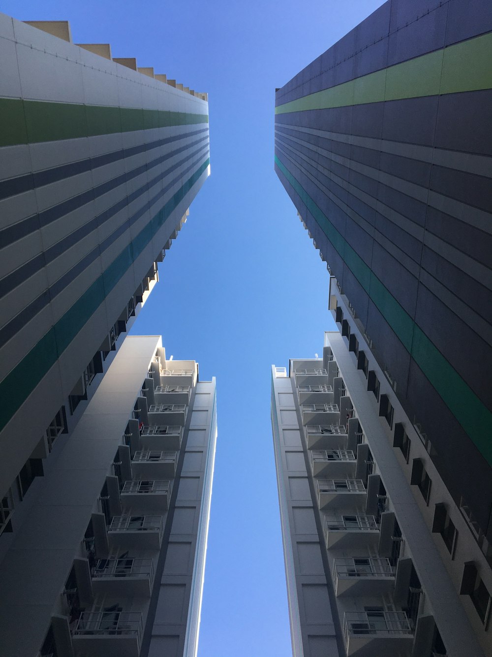 looking up at two tall buildings with balconies