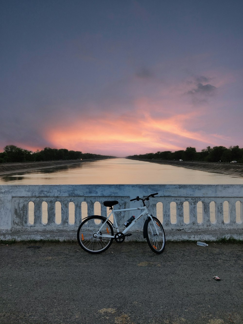 a bike parked on the side of a bridge next to a body of water