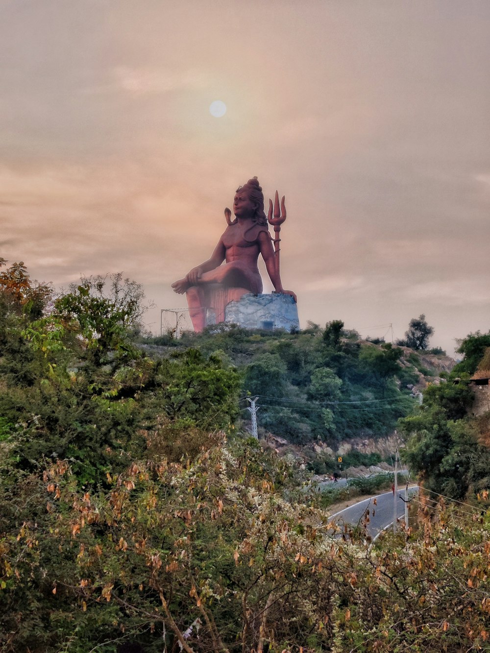 a statue of a woman sitting on top of a hill