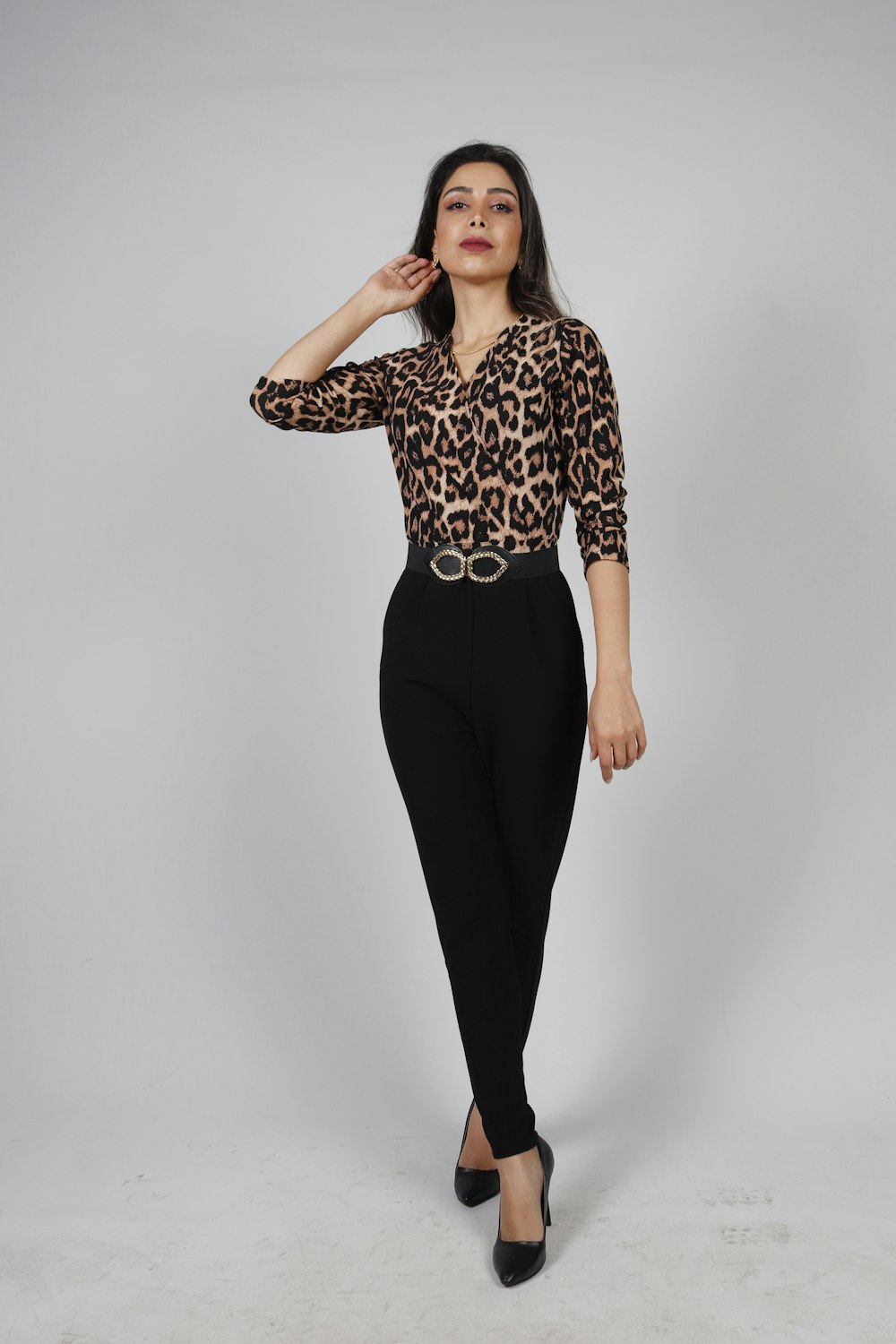 a woman wearing a leopard print shirt and black pants