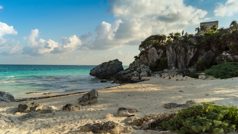 a sandy beach next to the ocean under a cloudy sky