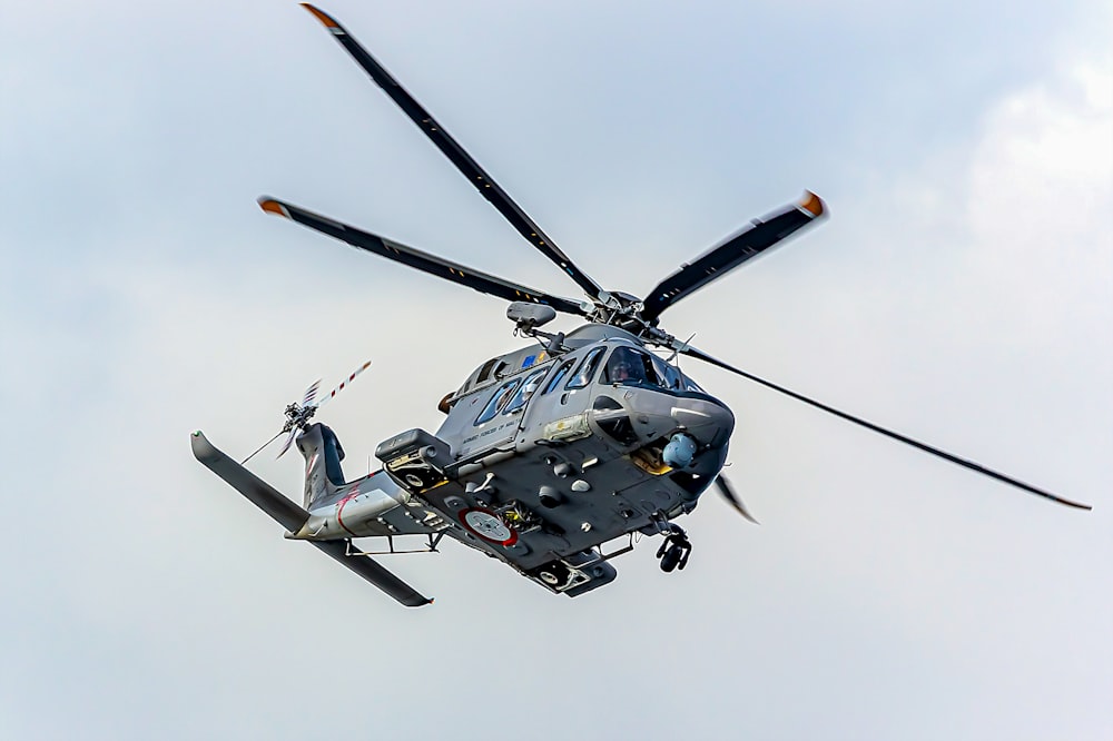 a helicopter flying in the sky with a person standing on the front of it