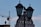 A decorative rooftop dome is framed by two lamp posts in the foreground, silhouetted against a sky with light clouds. A construction crane is visible on the left side, suggesting ongoing development.