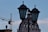 A decorative rooftop dome is framed by two lamp posts in the foreground, silhouetted against a sky with light clouds. A construction crane is visible on the left side, suggesting ongoing development.
