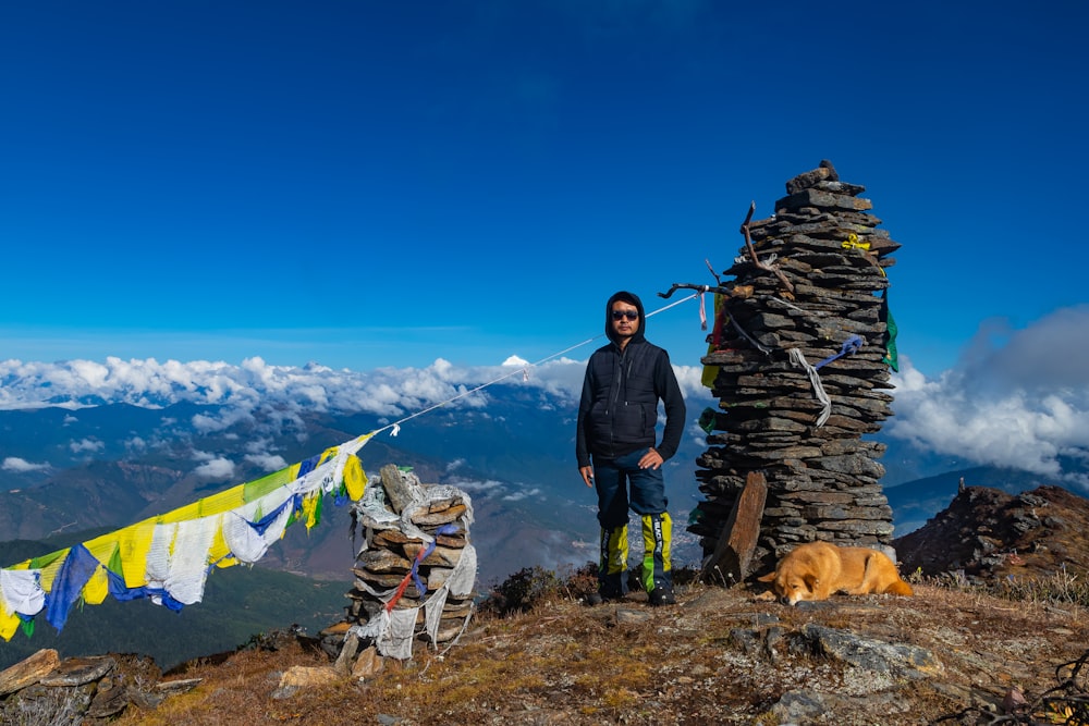 a man standing on top of a mountain next to a pile of rocks