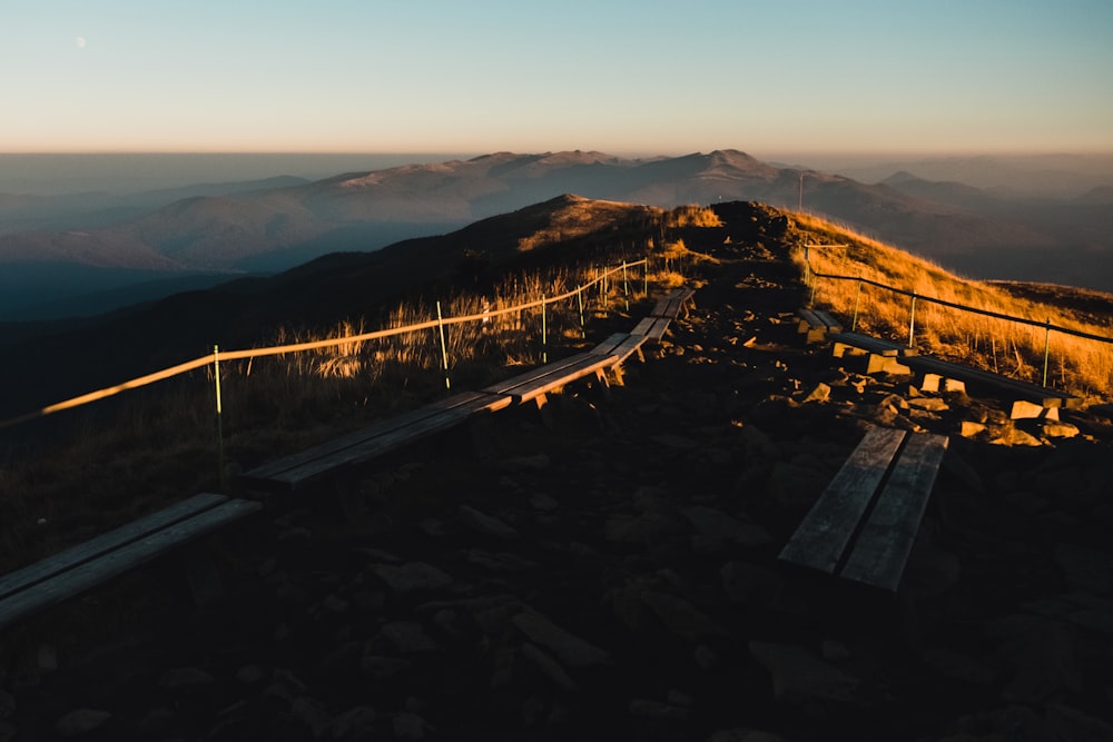 a wooden bench sitting on the side of a mountain