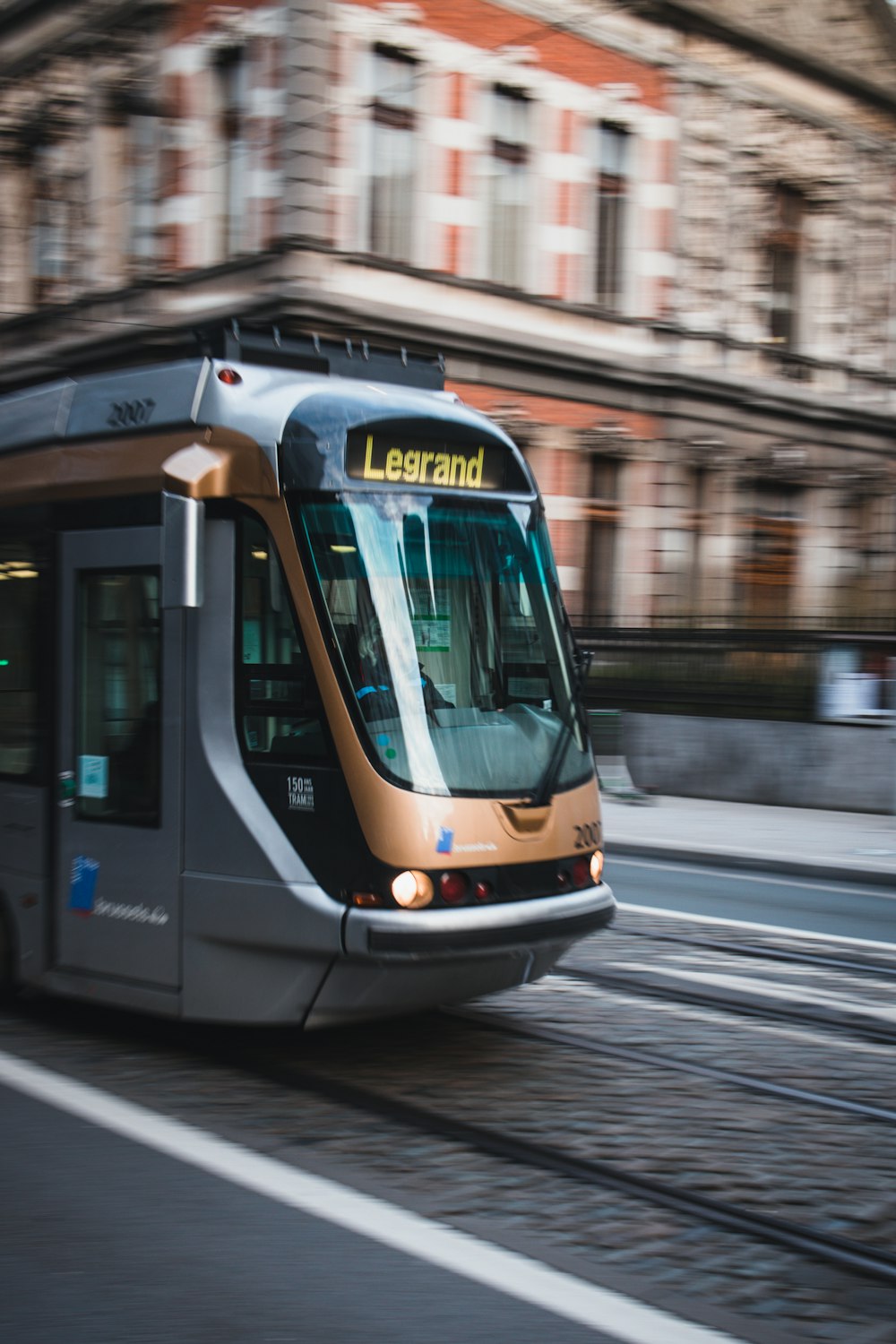 a train traveling down a street next to a tall building