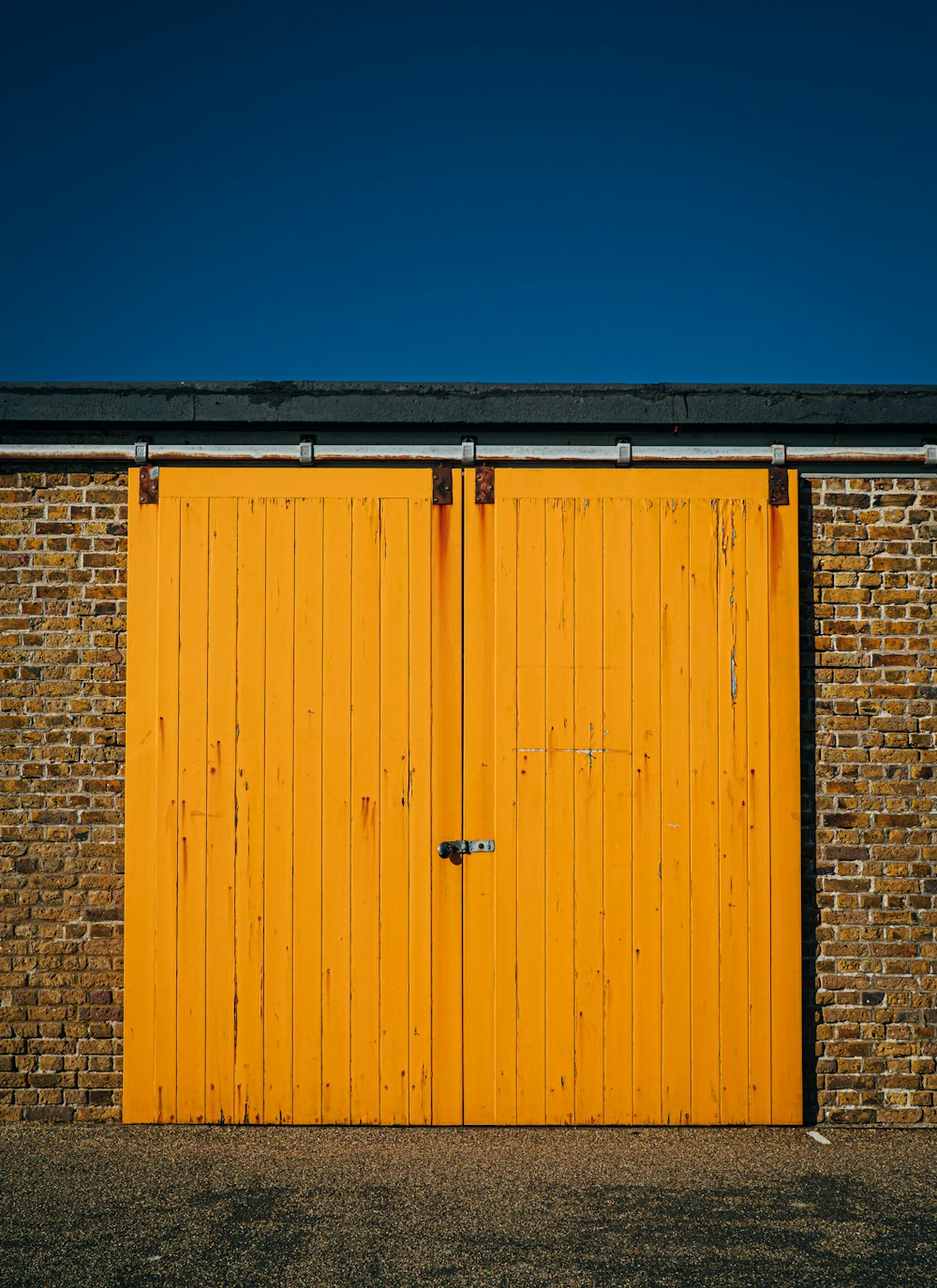 Una puerta de garaje amarilla con un edificio de ladrillo en el fondo