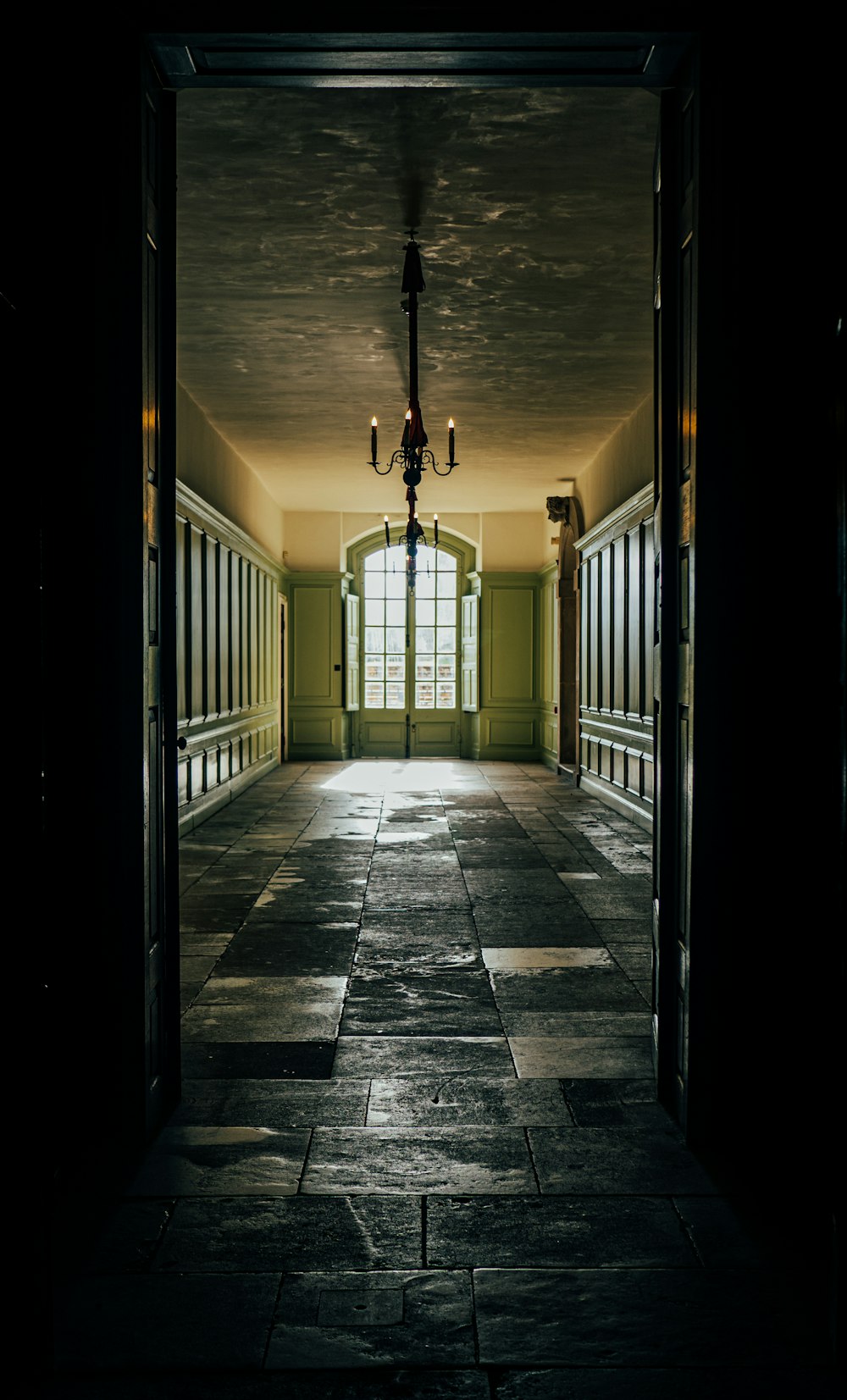 an empty hallway with a chandelier hanging from the ceiling