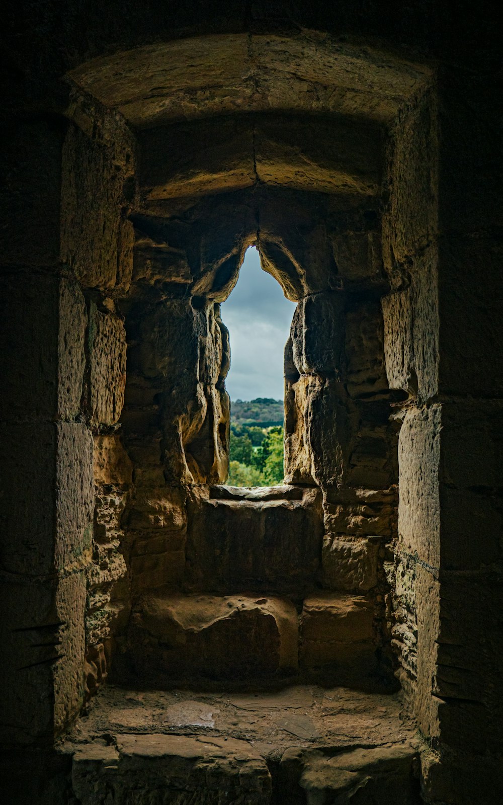 a window in a stone building with a view of a valley