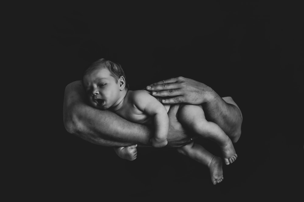 a black and white photo of a man holding a baby