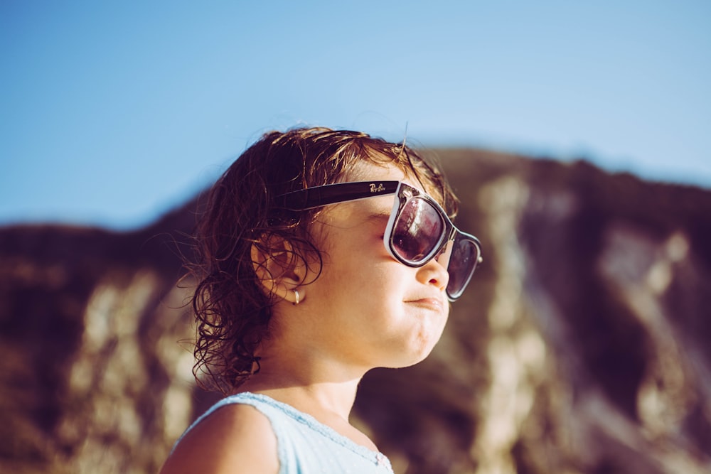 a little girl wearing sunglasses looking up into the sky