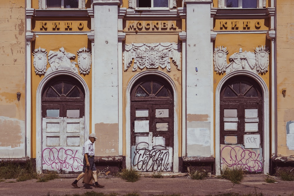 a man walking past a building with graffiti on it