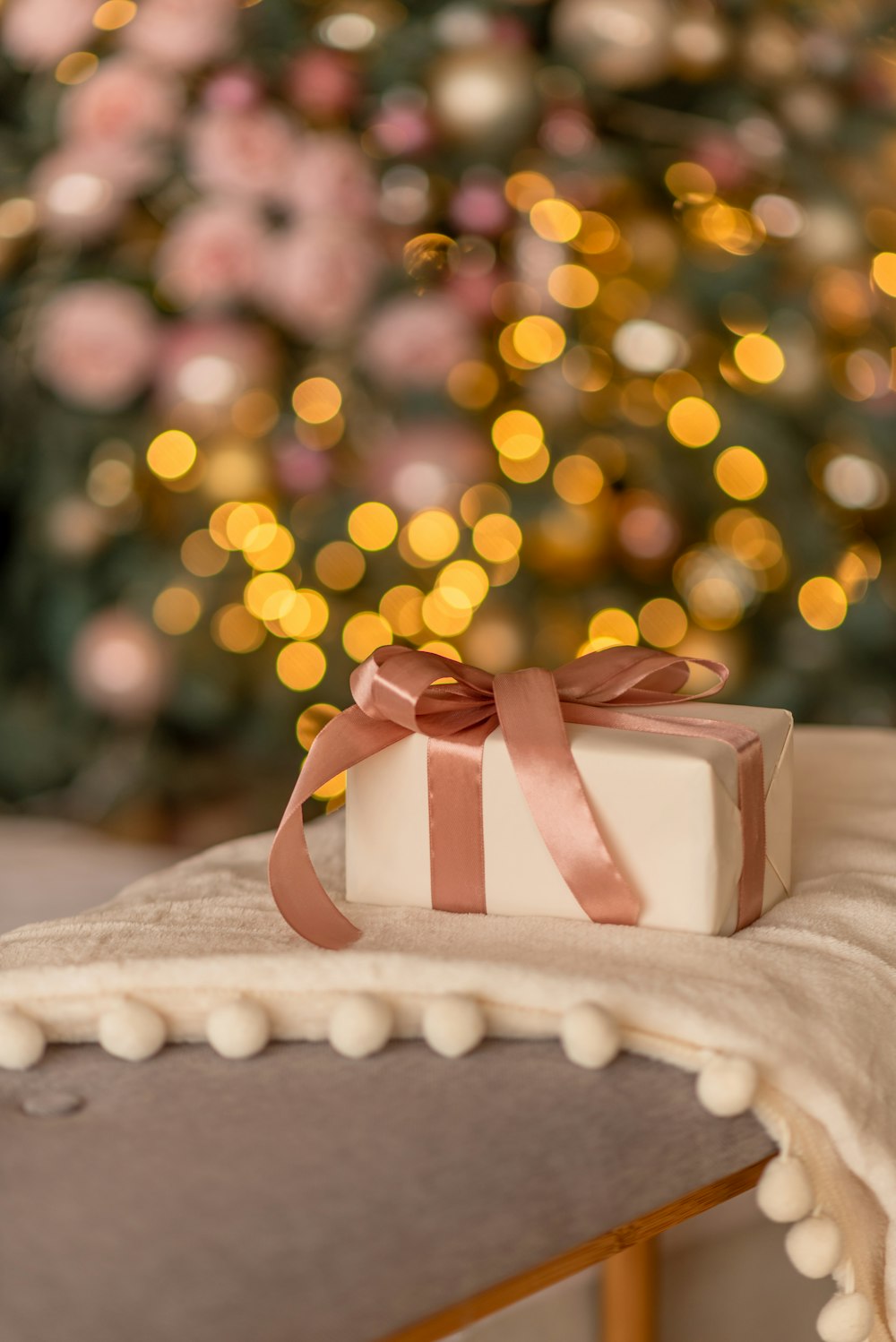 a present box sitting on a table with a christmas tree in the background