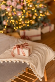 a present sitting on a bed with a christmas tree in the background
