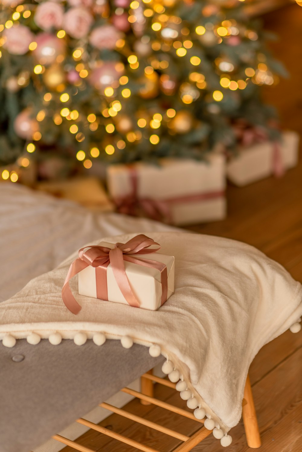 a present sitting on a bed with a christmas tree in the background