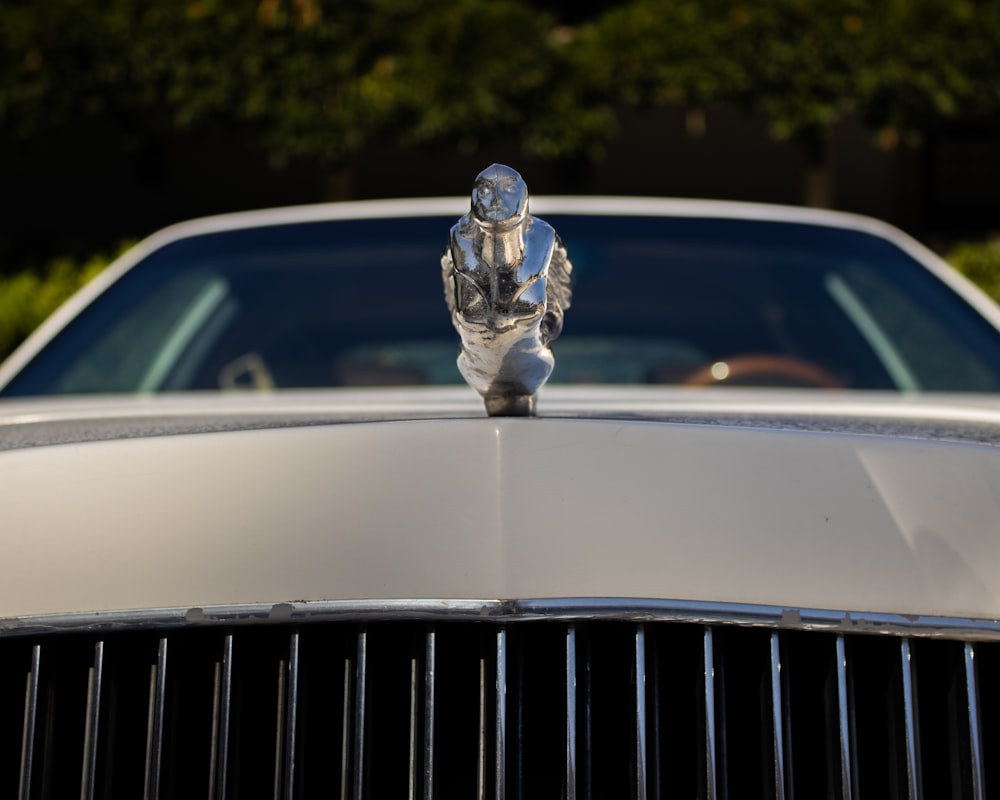 a silver car with a statue on top of it