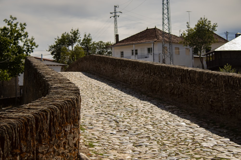 a cobblestone road with a house in the background