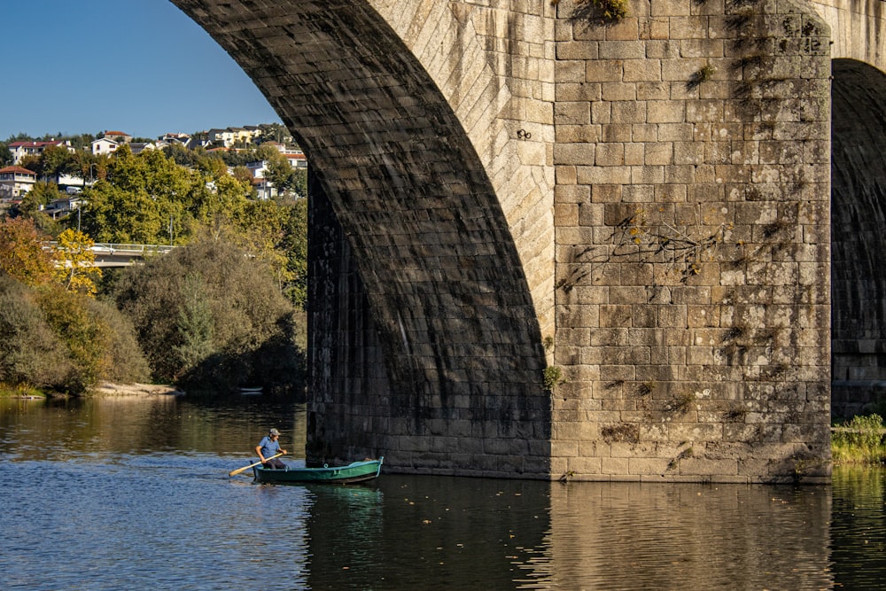 a person in a small boat under a bridge