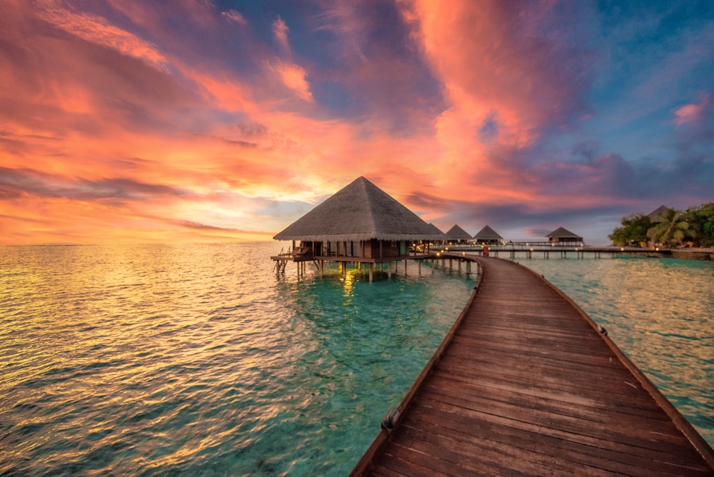 a dock leading to a hut in the ocean