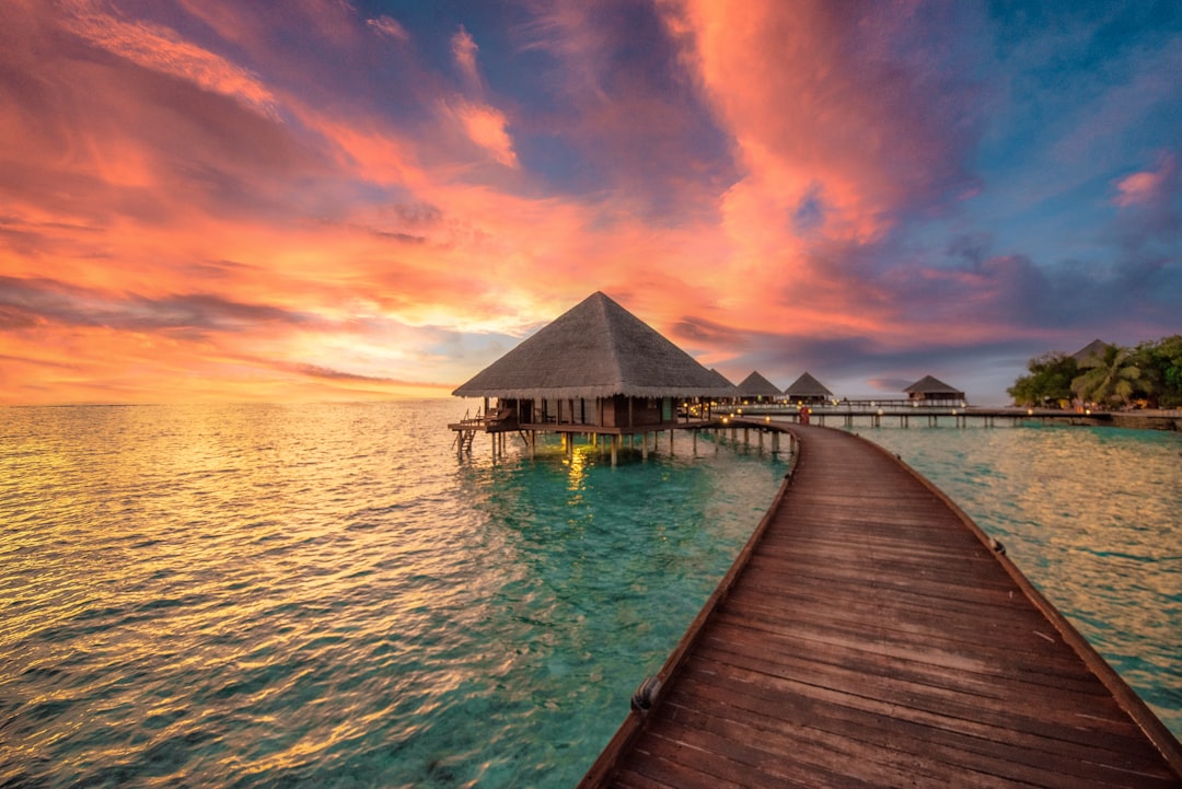 a dock leading to a hut in the ocean,