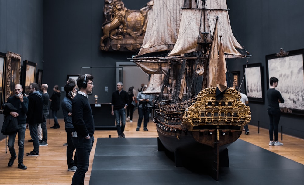 a group of people looking at a model of a ship