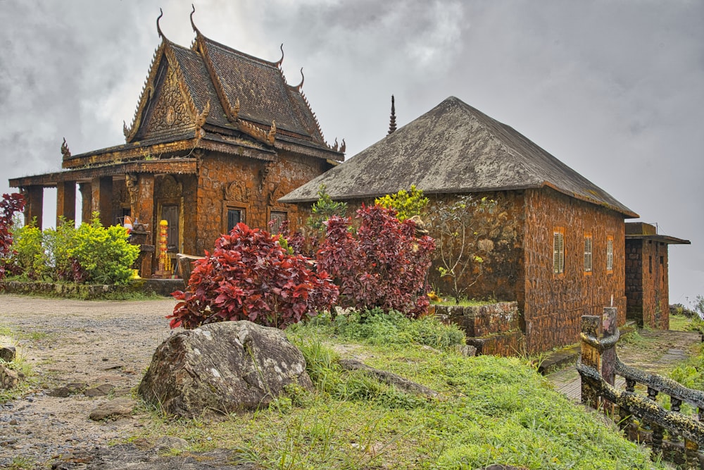 a stone building with a thatched roof next to a tree