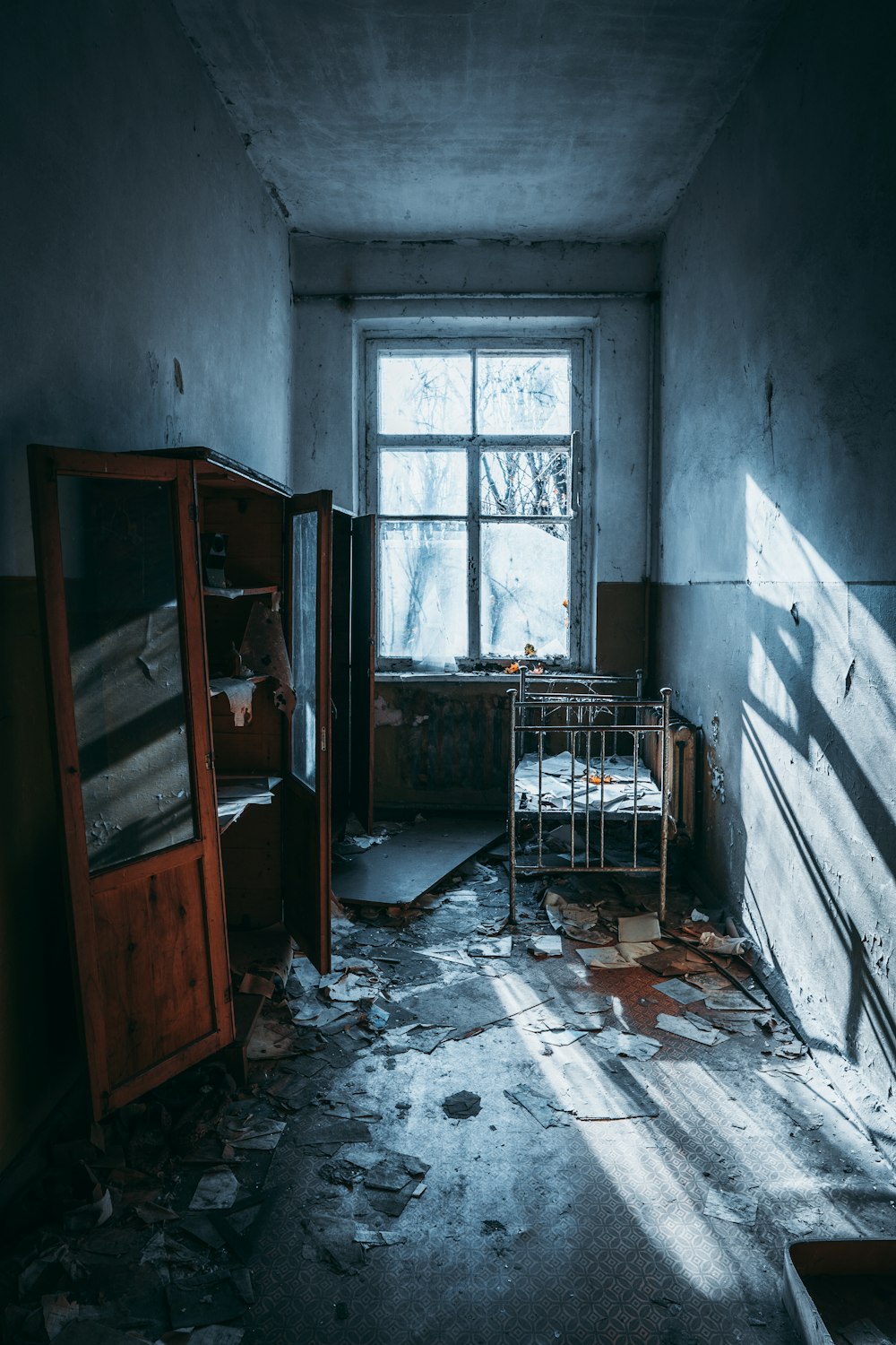 a run down room with a bed and a window