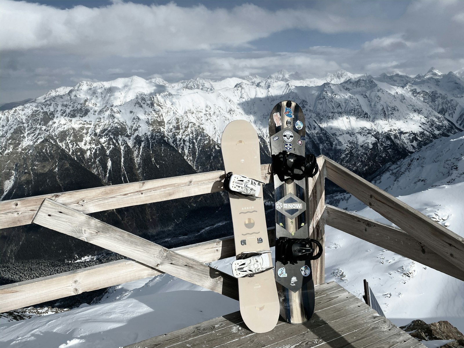 Snowboards standing in a rack against an alpine backdrop
