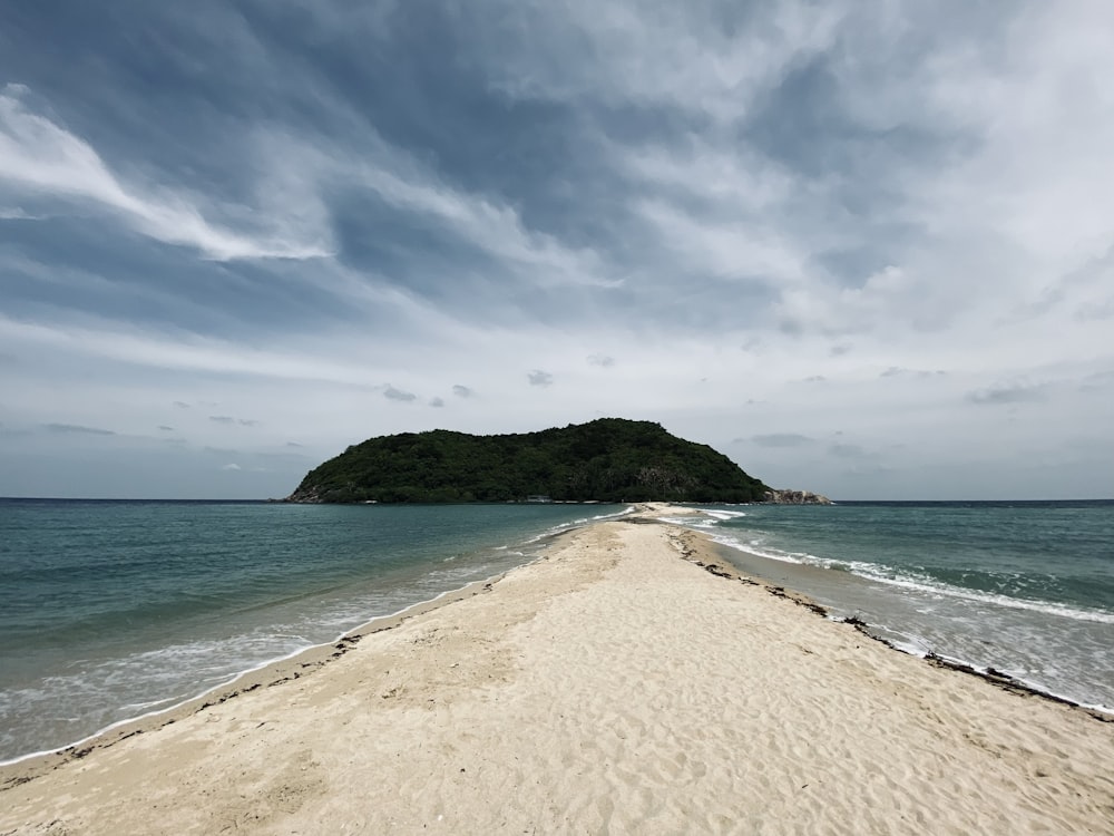 a sandy beach with a small island in the distance