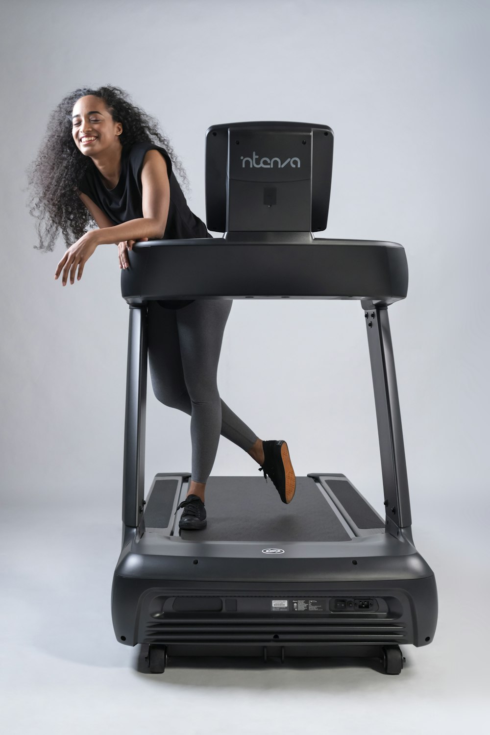 a woman standing on a treadmill with a laptop on top of it