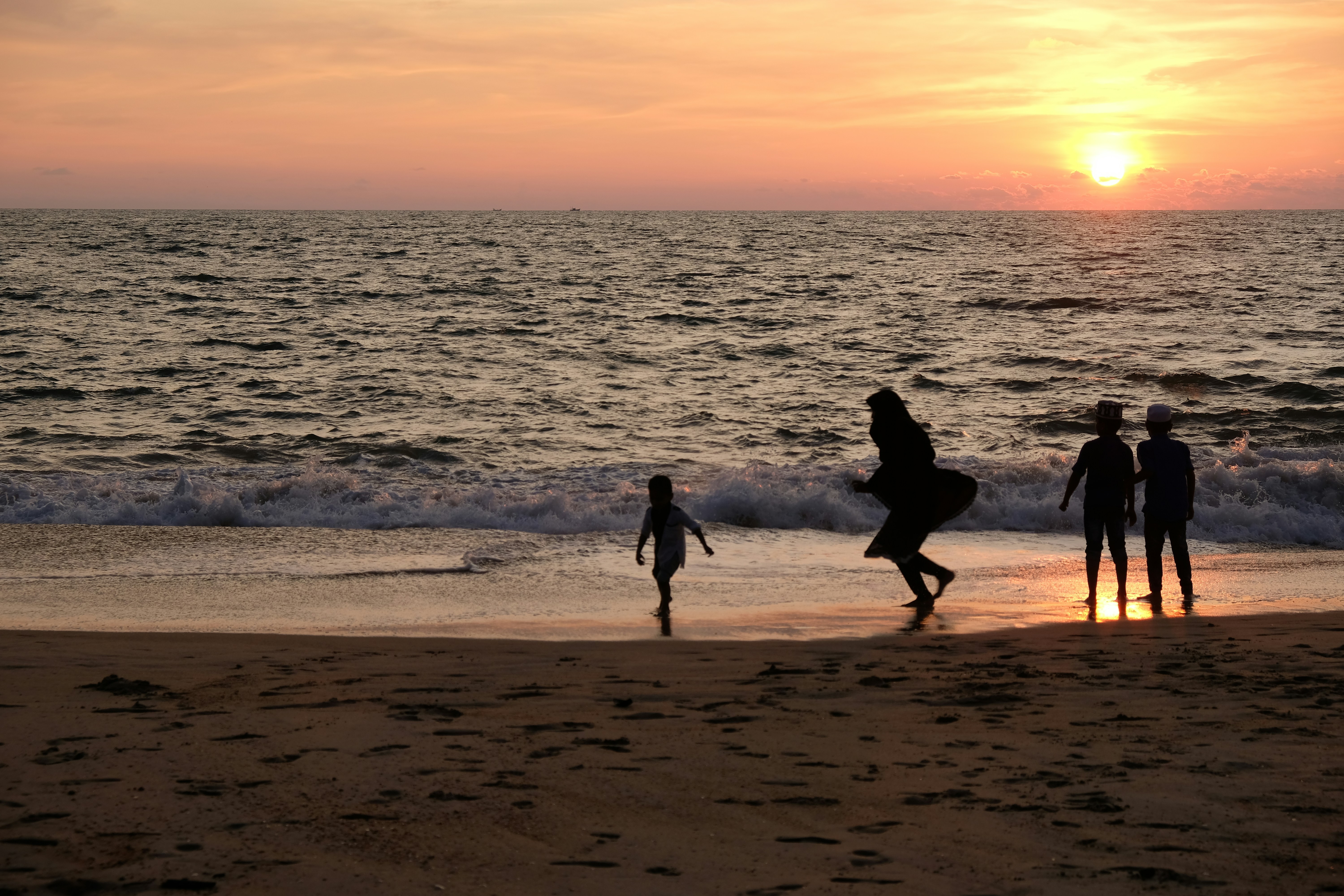 a group of people standing on top of a beach next to the ocean