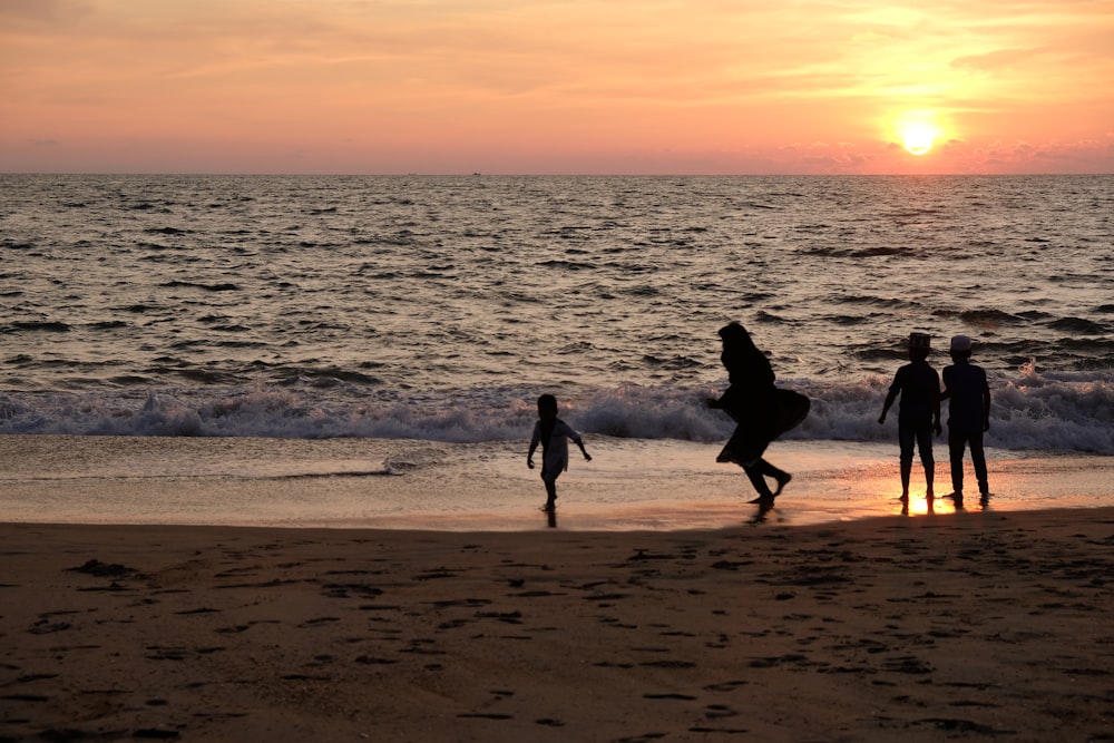 a group of people standing on top of a beach next to the ocean