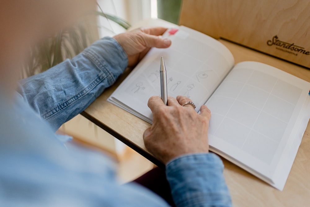 a person sitting at a table writing on a book