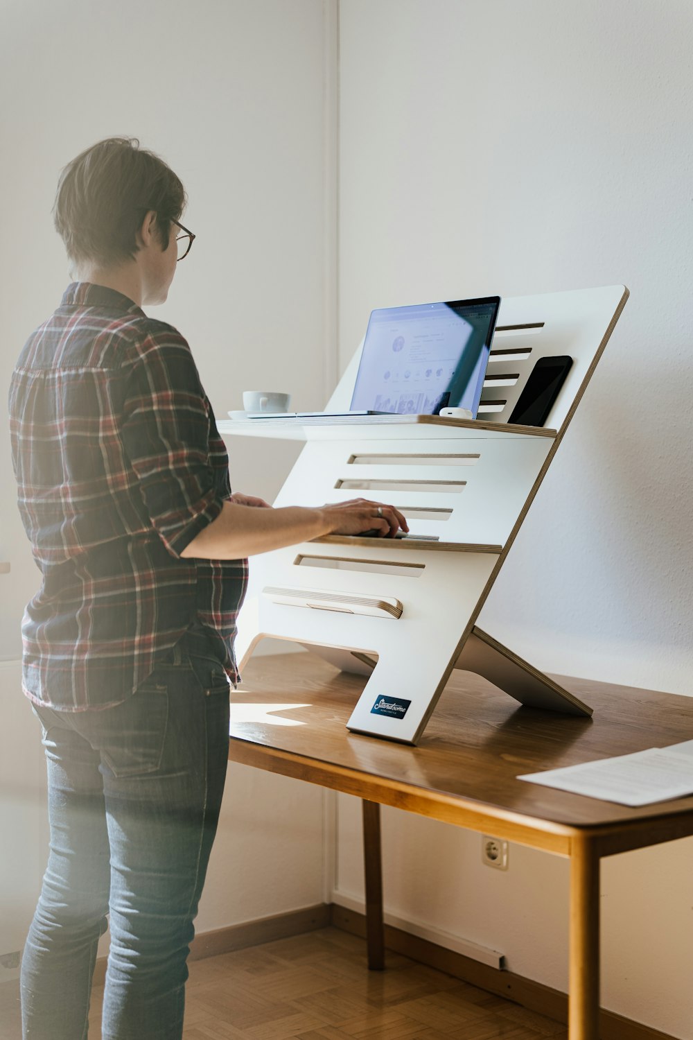 a person standing in front of a desk with a laptop on it