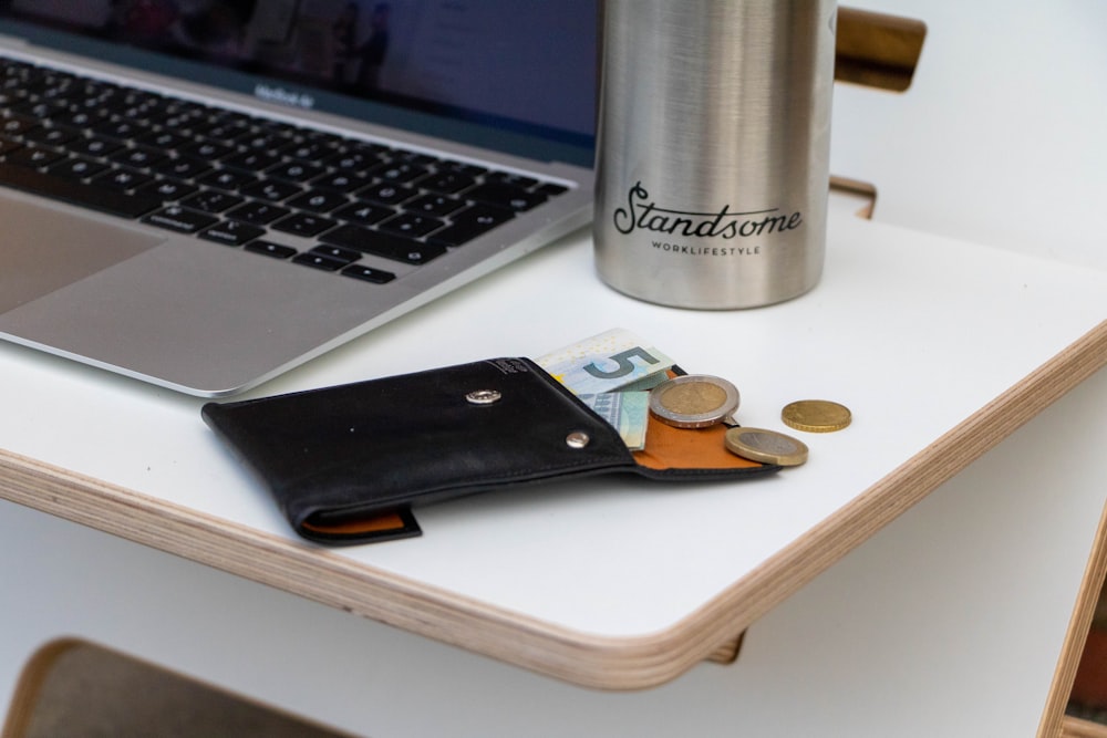a wallet sitting on a table next to a laptop