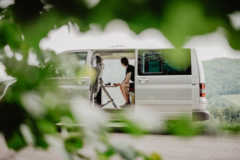 uma mulher sentada na parte de trás de uma van branca