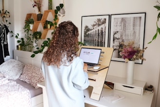 a woman standing in front of a desk with a laptop