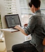 a man sitting at a desk using a laptop computer