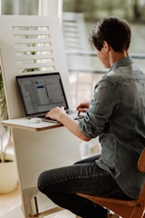 A cheerful employee working at a standing desk with plants nearby.