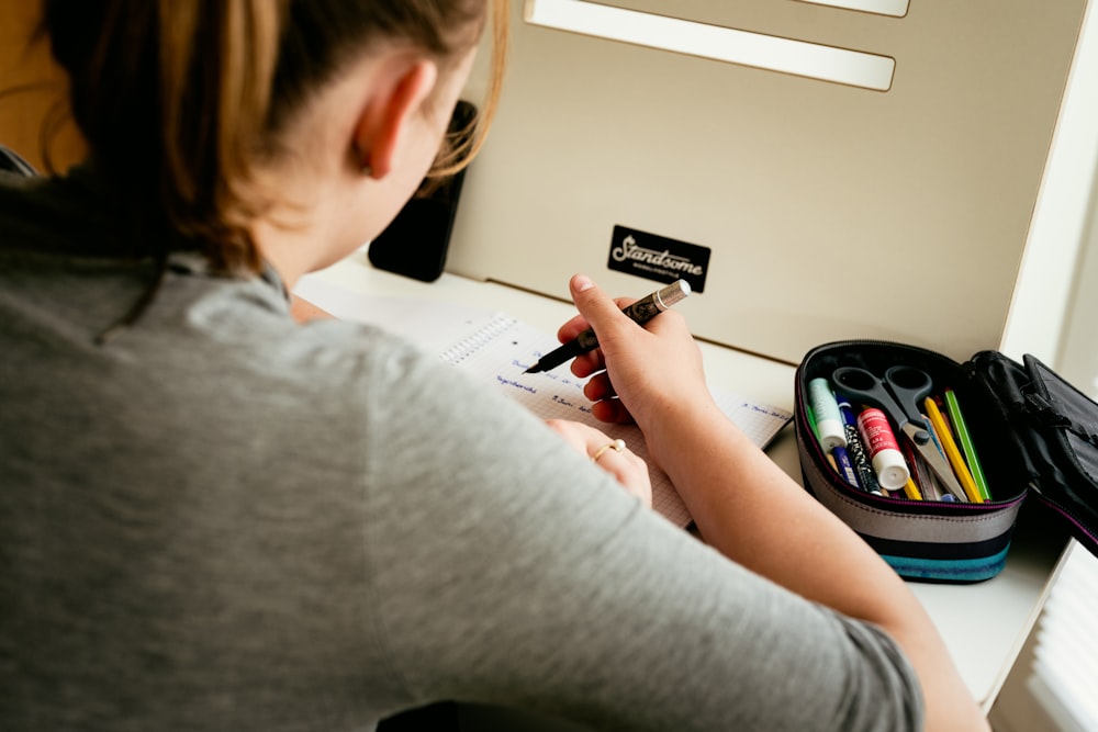 a woman sitting at a desk writing on a piece of paper